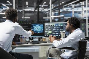Server room manager and employee in wheelchair use artificial intelligence to perform computing tasks. Data center team leader and engineer with disability use AI for machine learning workloads photo