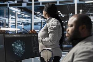 Data center employee monitoring system performance using PC, identifying malfunctions. African american server farm IT expert troubleshooting computer bugs, implementing optimizations photo