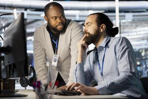 Data center manager supervising work done by employee verifying neural network parameters. Server hub supervisor overseeing worker inspecting configurations to ensure optimal performance photo