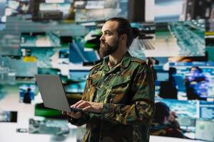 Male soldier operates in a virtual war zone using digital technology and threat detection tools, showcasing modern military strategy. Ensuring secure communications in active operations. photo