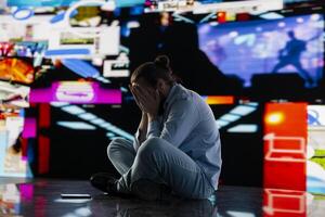 Paranoid guy suffers from emotional damage caused by obsessive social media use. Young man being overwhelmed by excessive information and comparison affecting his self esteem, manipulation. photo