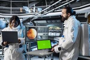 Astronaut checks green screen tablet interface before landing spaceship on Mars. Crew members looking at chroma key device during mission to red planet surface, testing human survival in deep space photo