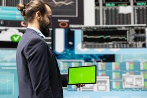 Male expert uses tablet with chroma key display leveraging dashboards, financial trends and KPI metrics optimizing company performance and planning for future success. Leadership. photo