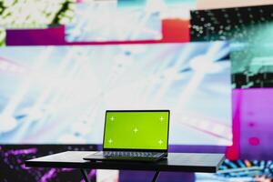 Empty space with a laptop showing green screen mockup next to artistic lights, creating a soundscape for nightlife ambiance and music culture. Spreading the visual art vibes and creativity. photo