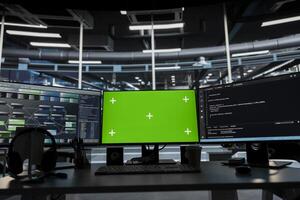 Green screen computer monitors in empty data center used to identify infrastructure malfunctions. Machine learning tech on chroma key PCs in server farm used to detect hardware failures photo