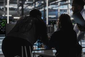 Server farm engineering team implementing and managing data backup solutions. Teamworking data center colleagues identifying and resolving technical errors, ensuring efficient recovery photo