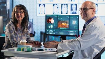 Doctor provides cancer screening to patient, discussing MRI scans and tumor growth. Early detection and preventative medicine emphasized for better health outcomes. Camera B. photo