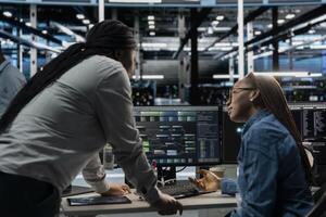 Data center manager supervising work done by engineer using artificial intelligence neural networks. Supervisor overseeing worker in server room using AI programming language to configure hardware photo
