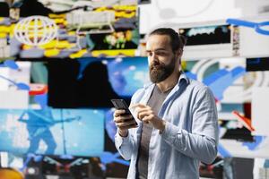 Young modern person focused on his smartphone app and scrolling on social pages, texting his friends and creating quality content for global reach. Trend setter cool guy on web connection. photo