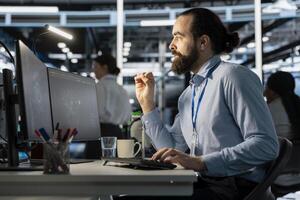 Programmer in data center using computer, doing software updates, verifying neural network parameters. Server room worker using PC to inspect configurations, ensuring optimal application performance photo