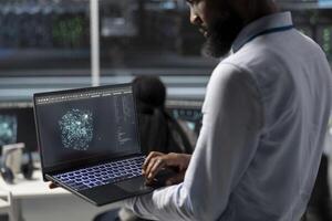 Data center engineer uses AI visualization tool on laptop to optimize resource allocation. Server hub IT expert uses artificial intelligence analysis on notebook to do maintenance photo