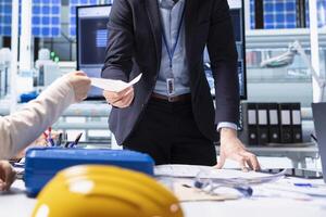Shareholders reading report of industrial production growth opportunities and technological insights found during research and development process. Factory manager offers investors documentation files photo