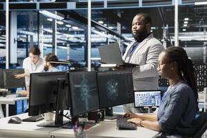 Data center IT experts using artificial intelligence neural networks technology. African american server farm facility software developers using AI programming language on computer to update hardware photo