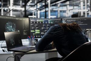 Exhausted server farm engineer falls asleep while looking at data analysis graph to reduce equipment failure. Tired data center worker exhausted after looking at AI visualization dashboard all day photo