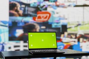 Laptop running isolated chroma key screen next to social media web design platforms, visual representation of trends and mobile interaction. Empty space with a device and online engagement. photo