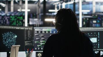 Server room programmer interpreting data analytics graphs, putting on headphones. Data center IT expert uses artificial intelligence tool showing system metrics, listening music, camera B photo