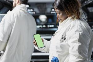 Scientists conduct visual data tests using chroma key smartphone aboard advanced starship during spaceflight. Cosmonauts perform orbital experiments, relying on isolated screen phone for analysis photo