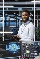 Cheerful man in server hub facility using artificial intelligence to perform demanding computing tasks. Jolly admin in data center uses AI technology for machine learning workloads photo