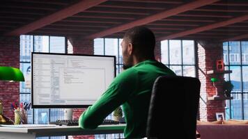 Black IT developer at PC coding and creating app software, implementing algorithms to fix errors. Engineer in loft working with code language, optimizing app performance. Camera B. photo
