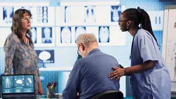 Healthcare expert conducts physical routine checkup on senior patient, addressing spinal issues and providing solutions for pain management and improved mobility in clinic. Camera B. photo