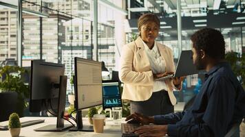 Manager in office ensuring worker hits key performance targets for revenue, profitability and operational efficiency. Corporate executive board member talks with employee, camera B photo