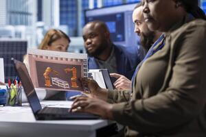 Photovoltaics factory managers look over schematics, planning work on facility machines using laptop. Solar panels plant shareholders look over assembly lines blueprints, working on notebook photo