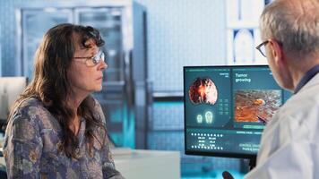 Physician consulting patient about MRI scan providing diagnostics insights into tumor growth and potential chemotherapy options in modern healthcare office. Camera B. photo