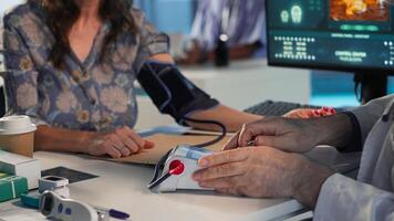 Senior physician measuring blood pressure, using professional tools at clinical consultation. Old doctor does tension reading and heartbeat measurement. Camera B. photo