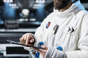 Close up of astronaut running telemetry software on tablet to confirm suit integrity. Orbital station crew member testing gear during routine equipment check, reviewing onboard analytics photo