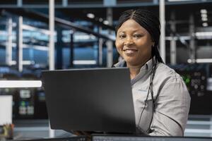 Portrait of smiling data center software developer using artificial intelligence neural networks. Cheerful server farm worker uses AI programming language on computer, configuring specialized hardware photo