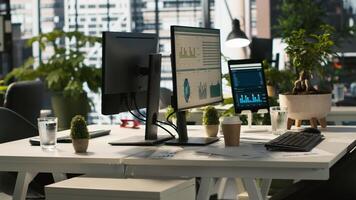 Business graphs and performance metrics on monitors in workplace, handheld camera shot. Office desk in bright corporate environment with monitors displaying data analytics, panning shot photo