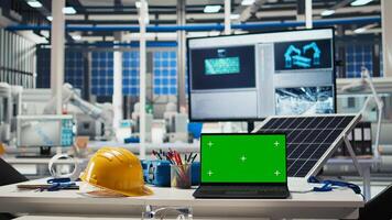 Green screen laptop in factory used to monitor performance of robot arms manufacturing solar panels. Chroma key notebook in empty industrial facility used to inspect photovoltaics machines photo