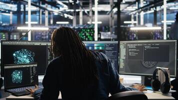 Data center administrator using machine learning algorithms to analyze large datasets. Server farm worker using AI neural networks on computer to recognize data patterns, camera A photo