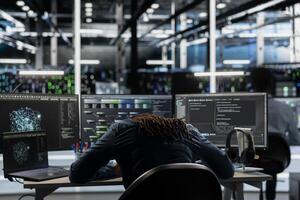Exhausted server farm engineer falls asleep while using AI algorithms to analyze large datasets. Tired data center worker exhausted after using deep learning to recognize patterns in facility data photo