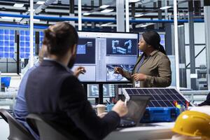 Shareholders collaborate on renewable energy investments, looking at data on display. Photovoltaics facility management team looking at manufacturing equipment specs on monitor, doing brainstorming photo