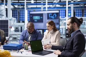 Factory researching team analyzing data, reviewing system health metrics with mockup laptop. Industrial plant management executives troubleshooting technical issues using chroma key notebook photo