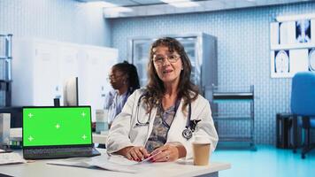 Physician doing checkup routine with patient next to chroma key screen, discussing about medicine and wellness. Man using health insurance for consultation with medic. Camera A. photo