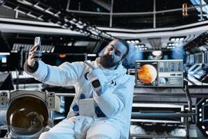 Cosmonaut doing selfies with smartphone during Mars expedition for future of mankind. Astronaut taking pictures using phone in spaceship, exploring red planet to support human life beyond Earth photo