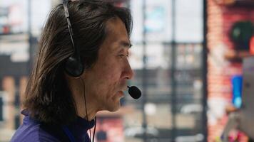 Closeup of call center agent helping customers regain access to accounts, resetting passwords. Experienced Asian worker in diverse customer center assisting clients needing help, camera A photo
