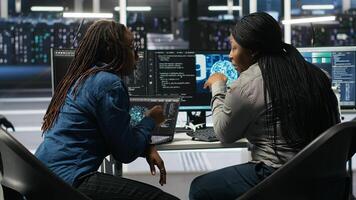 Data center coworkers doing brainstorming, using artificial intelligence machine learning to configure equipment. IT experts cooperating in server room, working on optimizing systems, camera B photo