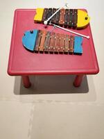 Two bonerundo fish xylophone on a red table. This musical instrument is designed for children. Made of wooden sticks of different lengths and colors, arranged in the shape of a fish. Copy space. photo