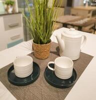 Composition with tea set and rattan vase on the white table. Preparation for a tea party with friends or relatives. Afternoon tea time. photo