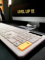 Computer monitor with Level Up written on it and keyboard. Enter key is yellow to indicate the action to be taken. Motivation, self-development and education concept. photo