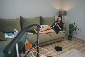 woman relaxing with smartphone during morning beauty routine with japanese chin dogs at home, clothes rack photo