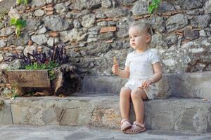 Child enjoying snack on stone steps surrounded by greenery in a sunny outdoor setting photo