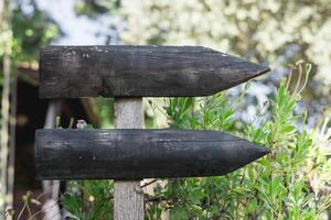 Wooden directional signposts in a garden showing two arrows toward different paths photo
