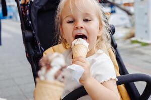 Toddler girl enjoys ice cream while exploring the marina during summer trip with her family photo