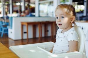 Young child in high chair enjoying a meal at a family-friendly restaurant during the day photo