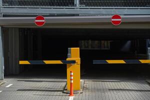 Parking spaces in the underground garage. entry and exit to the garage Barrier at the parking lot exit of a building. View of a car barrier gate at the entrance of a building. photo