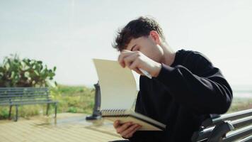 Man Searching For Inspiration And Ideas To Write On The Bench Near The Sea video